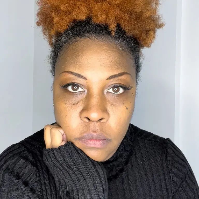 A portrait of an artist staring at the camera with a white background