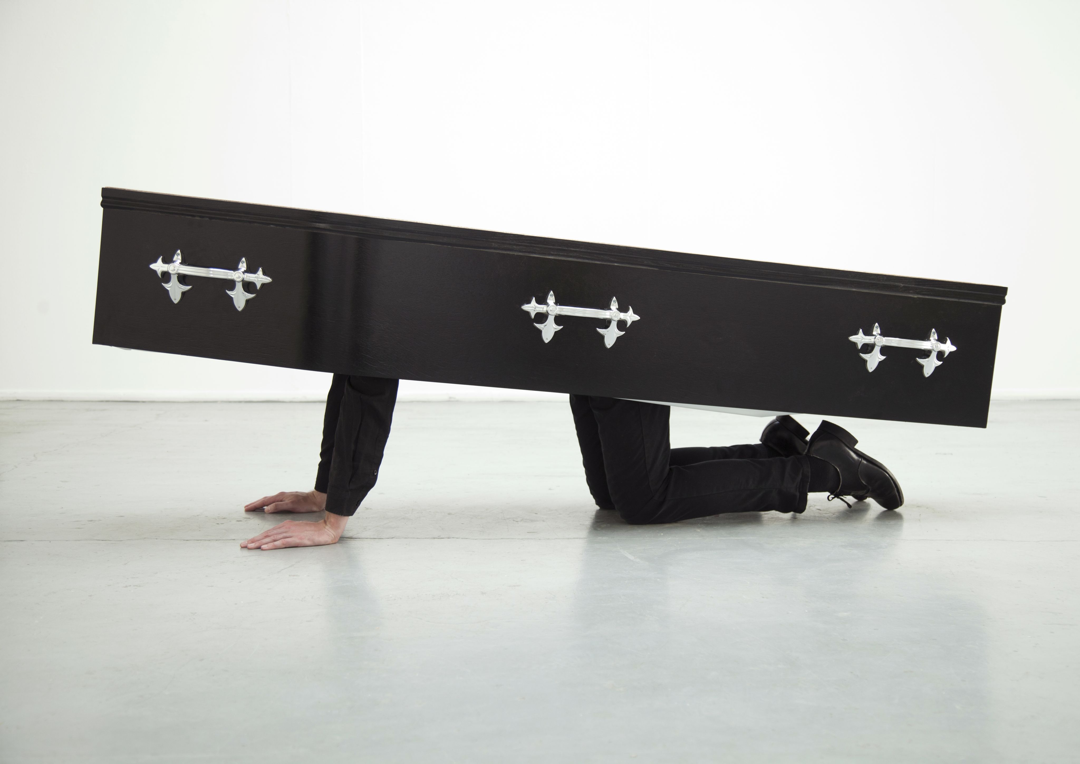 A figure in a coffin crouches on the ground