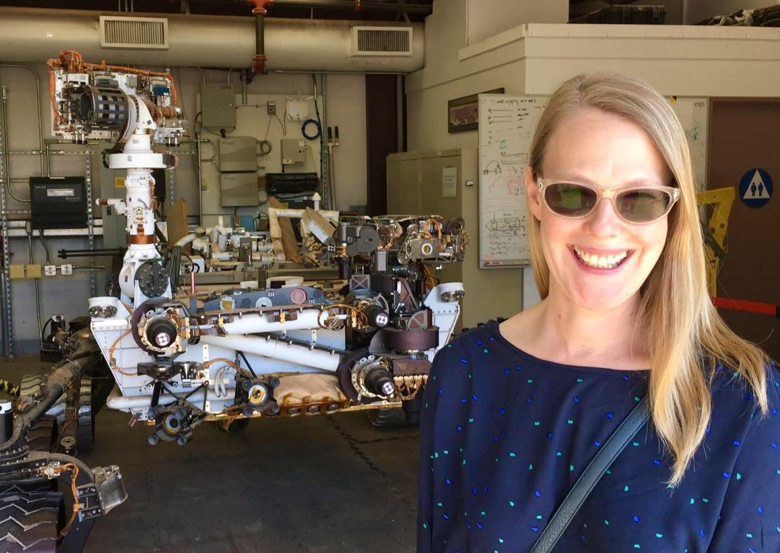 A woman stands in front of a robotic installation
