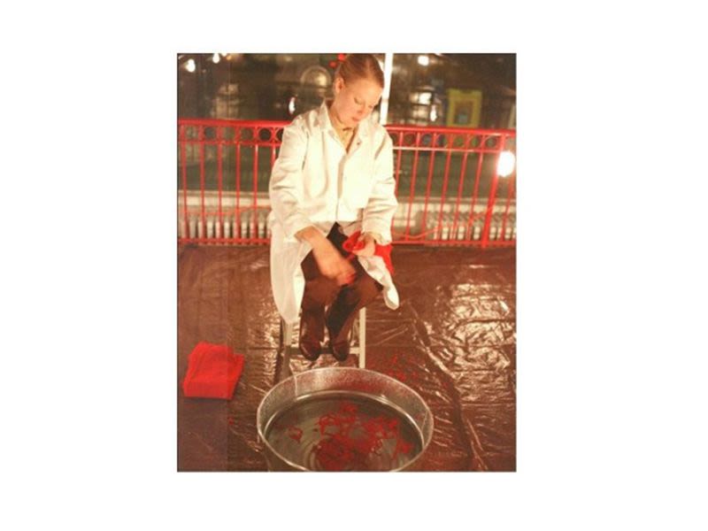 An artist in a white coat stands over a vat of water