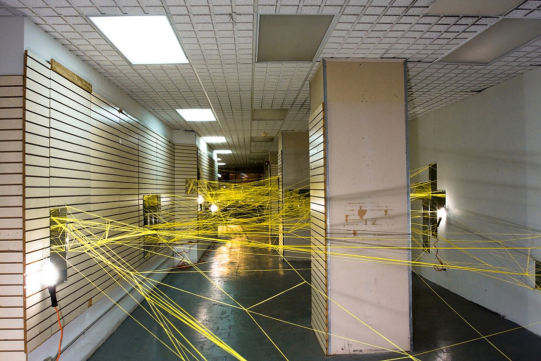 Yellow threads weave between an empty storefront