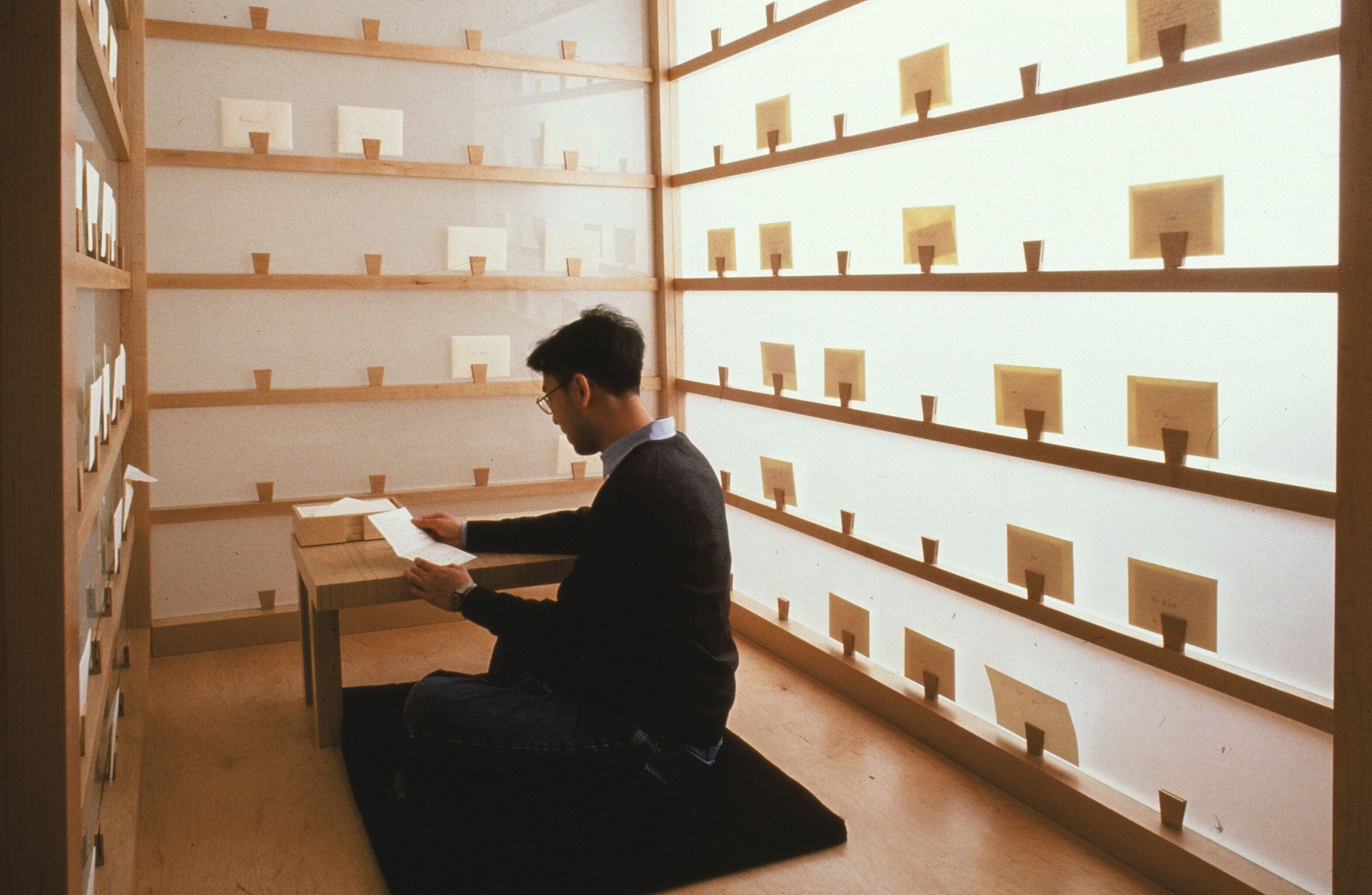 Someone sits in a small room with paper lining the walls 