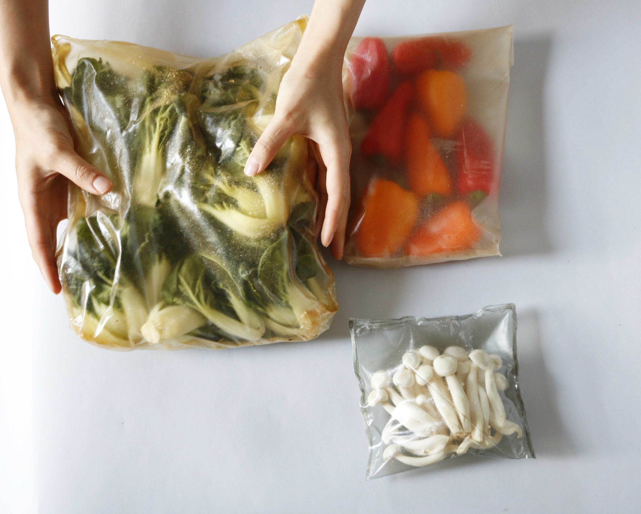 A pair of hands putting vegetables and mochi in PermaPak