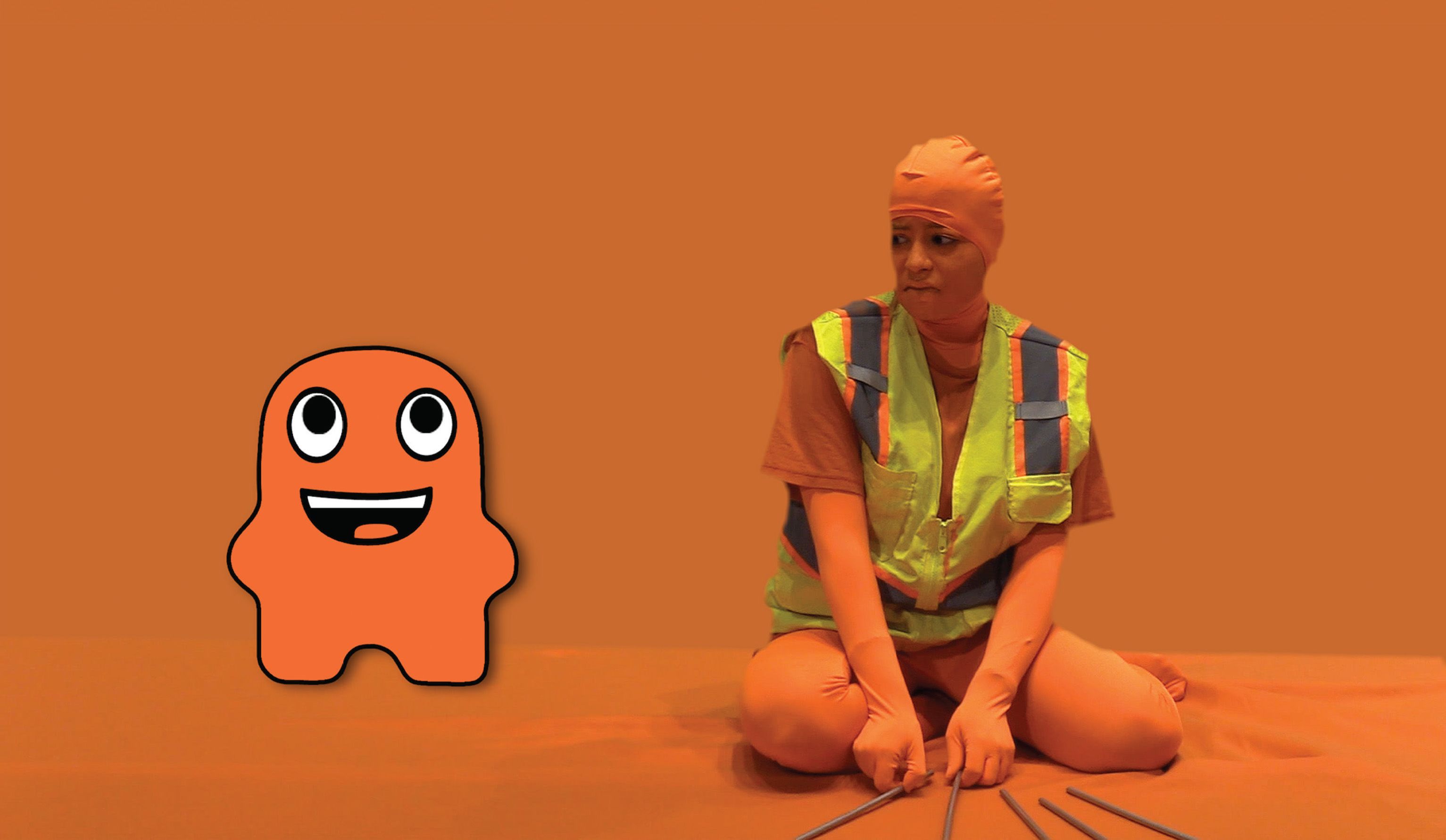 A person in all orange with a bright neon safety vest sitting on the floor in an all orange room next to a cartoon orange blob