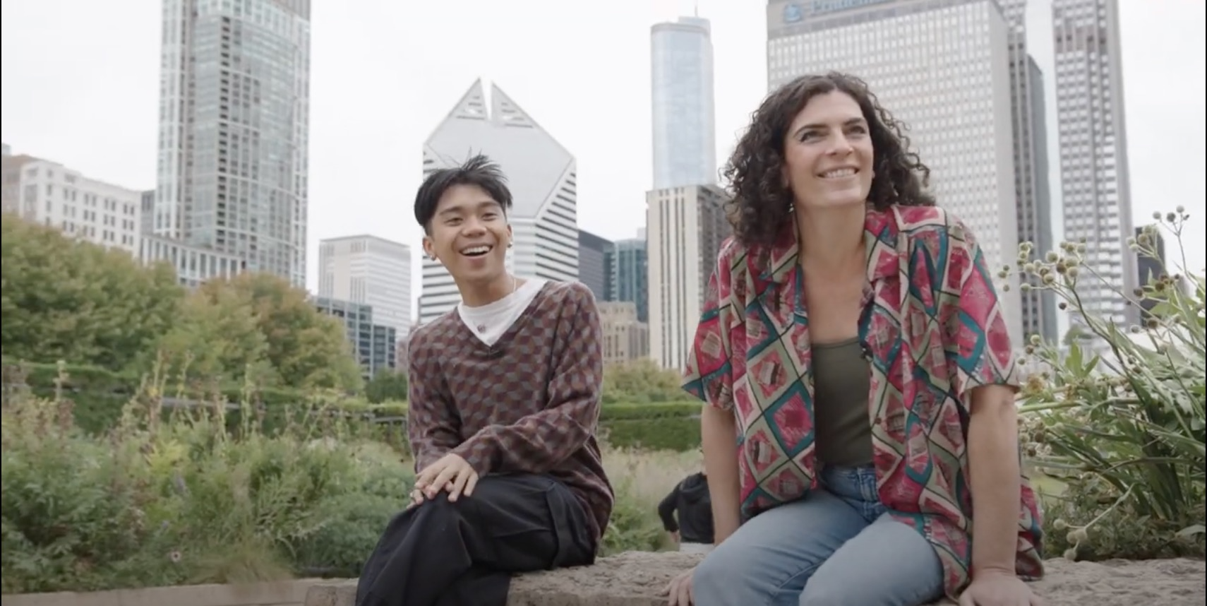 Two people sitting on a rock in front of the Chicago skyline.