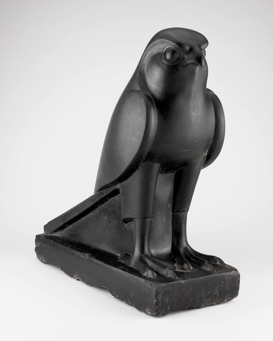 A black, matte statue of a falcon photographed on a white background