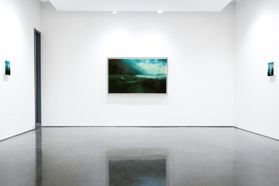 A modern white gallery space displaying three photographs on the wall