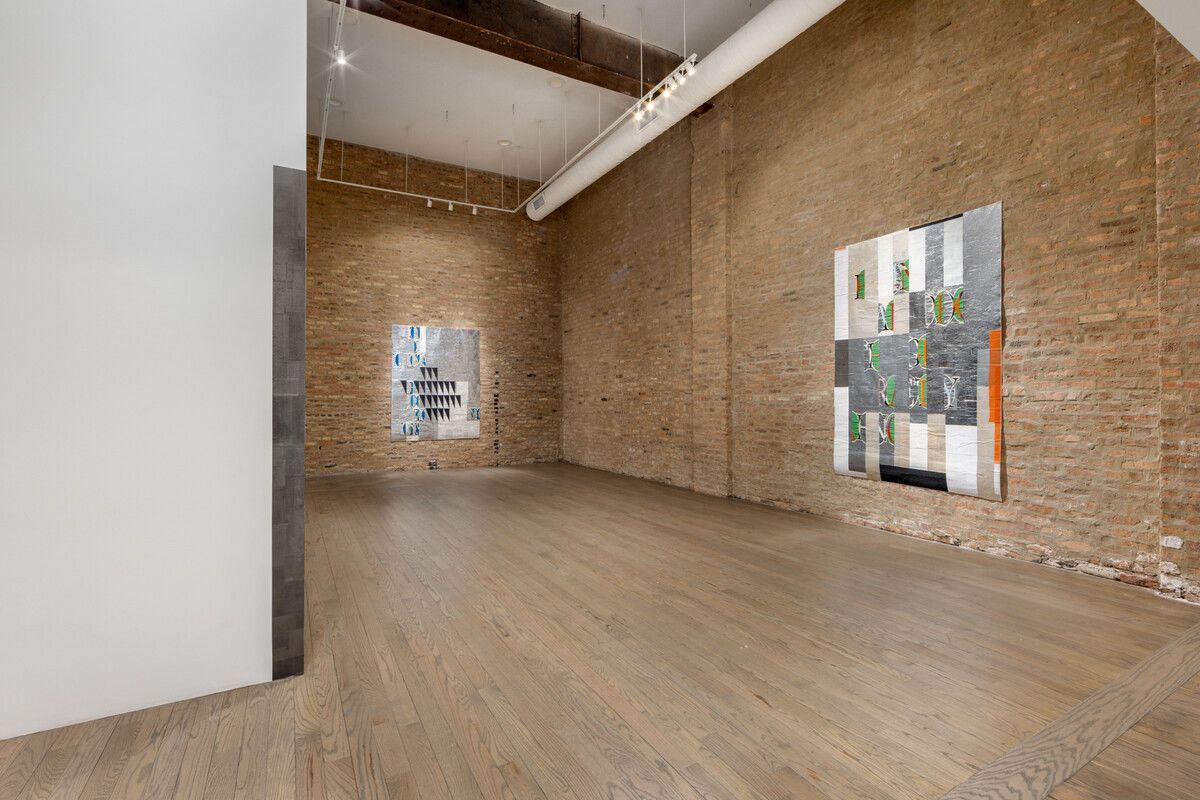 A brick-walled gallery space with two pieces hung on the wall. 
