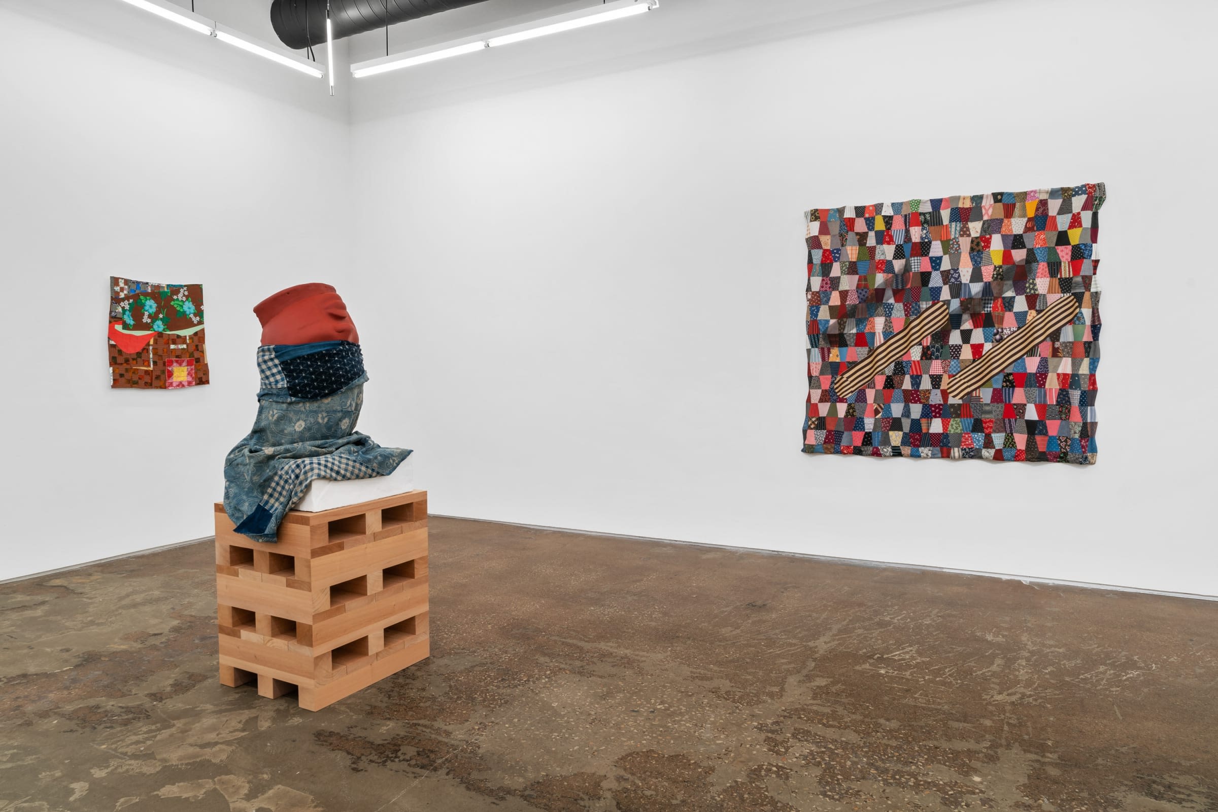 A gallery space featuring a sculpture and two abstract wall pieces