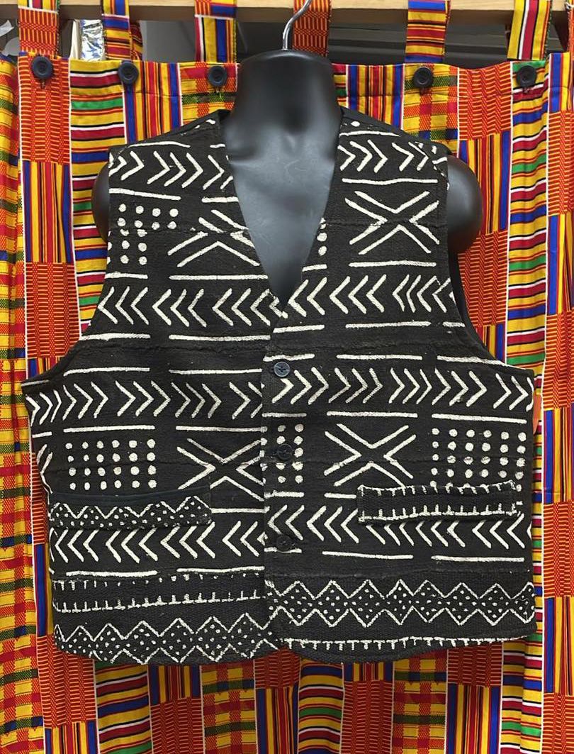 A vest in a black and white print hung over brightly colored fabric