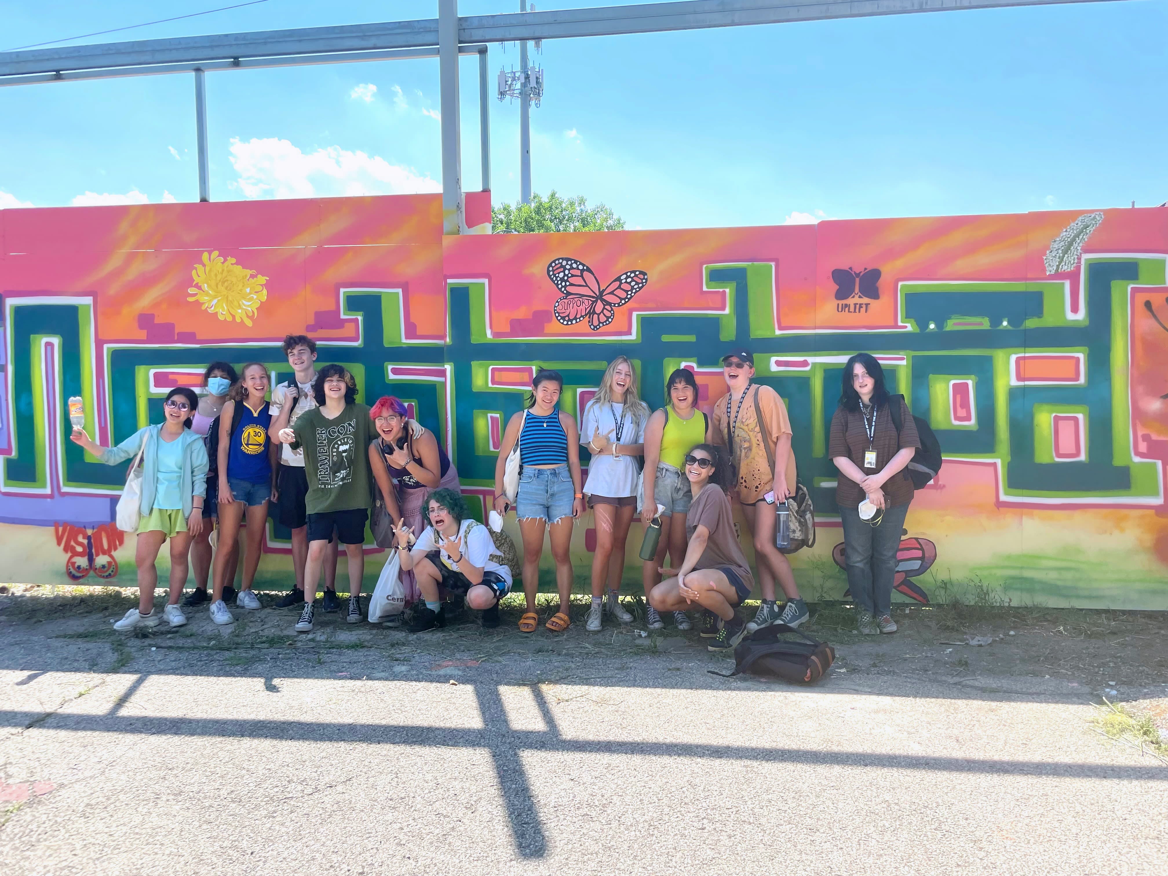 The class poses in front of a mural
