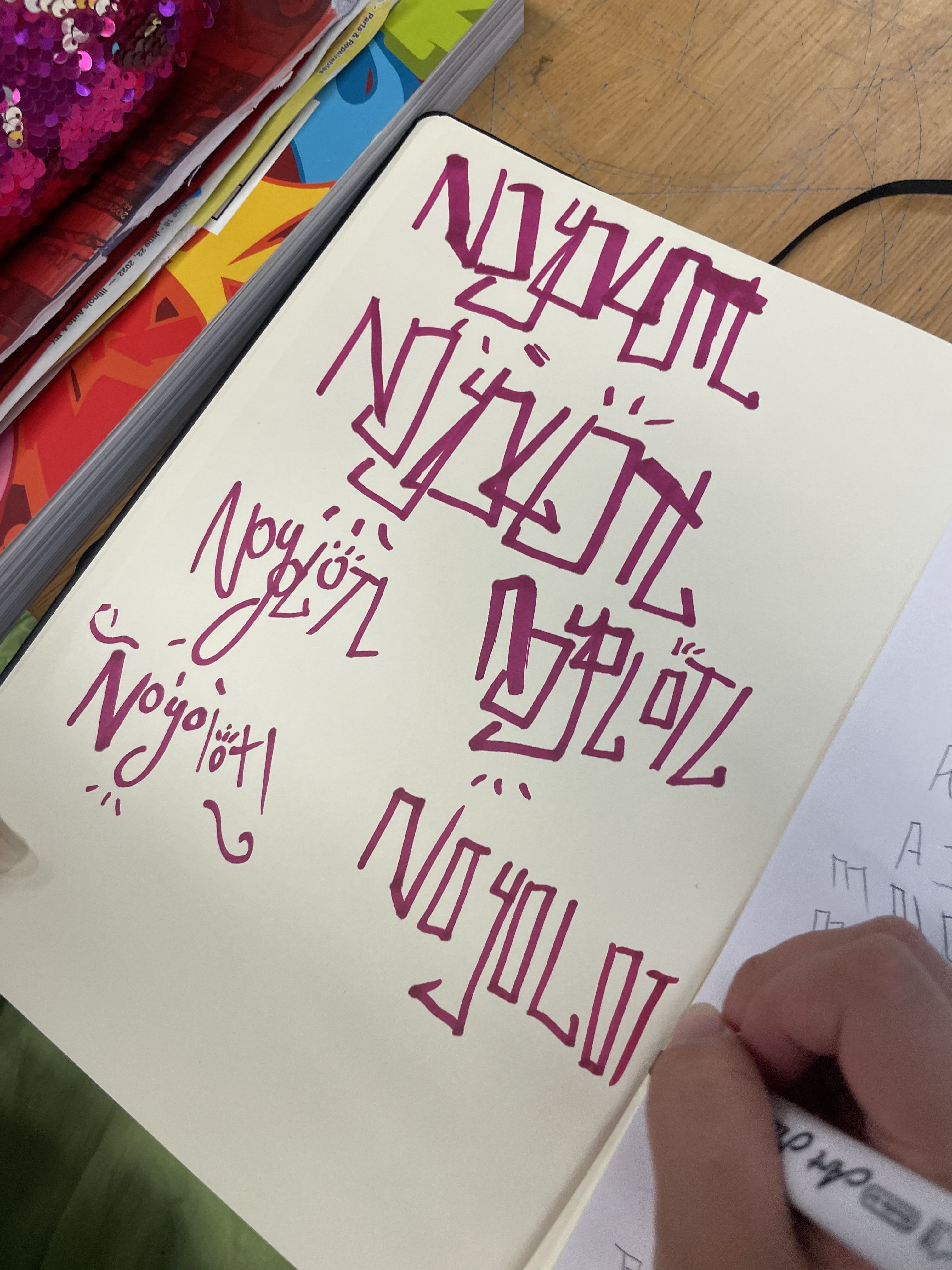 A hand practicing lettering in a sketchbook