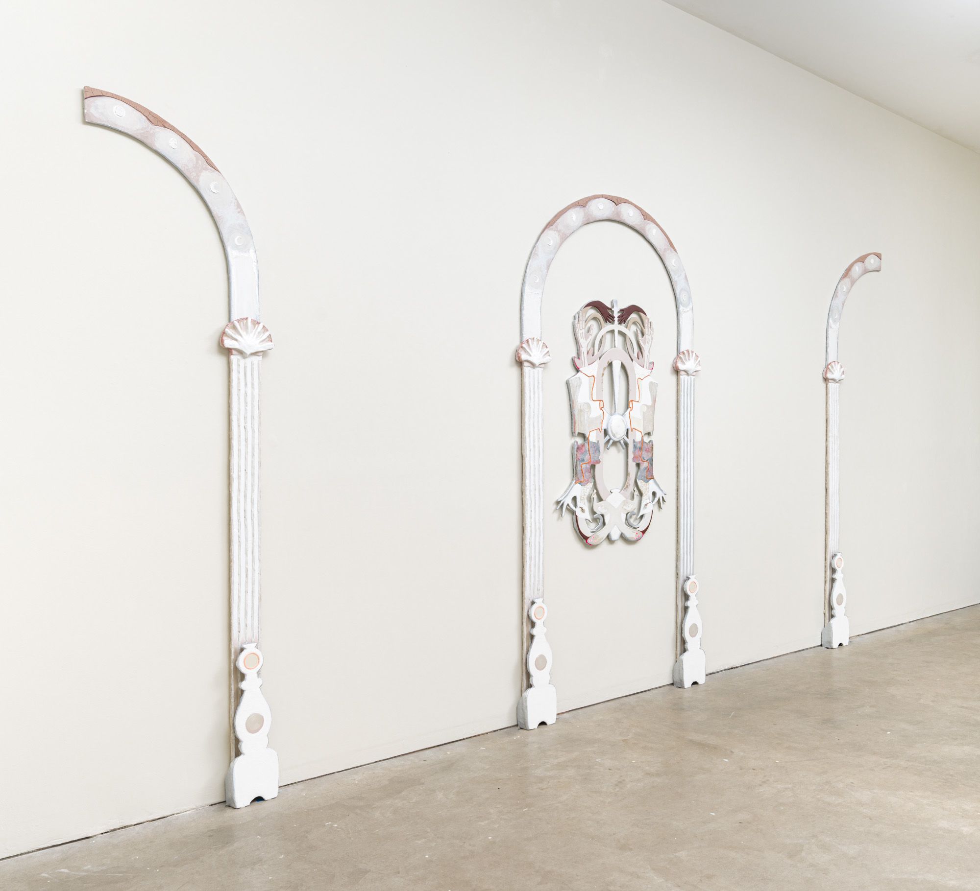 Tall, flat architectural sculptures line a gallery wall
