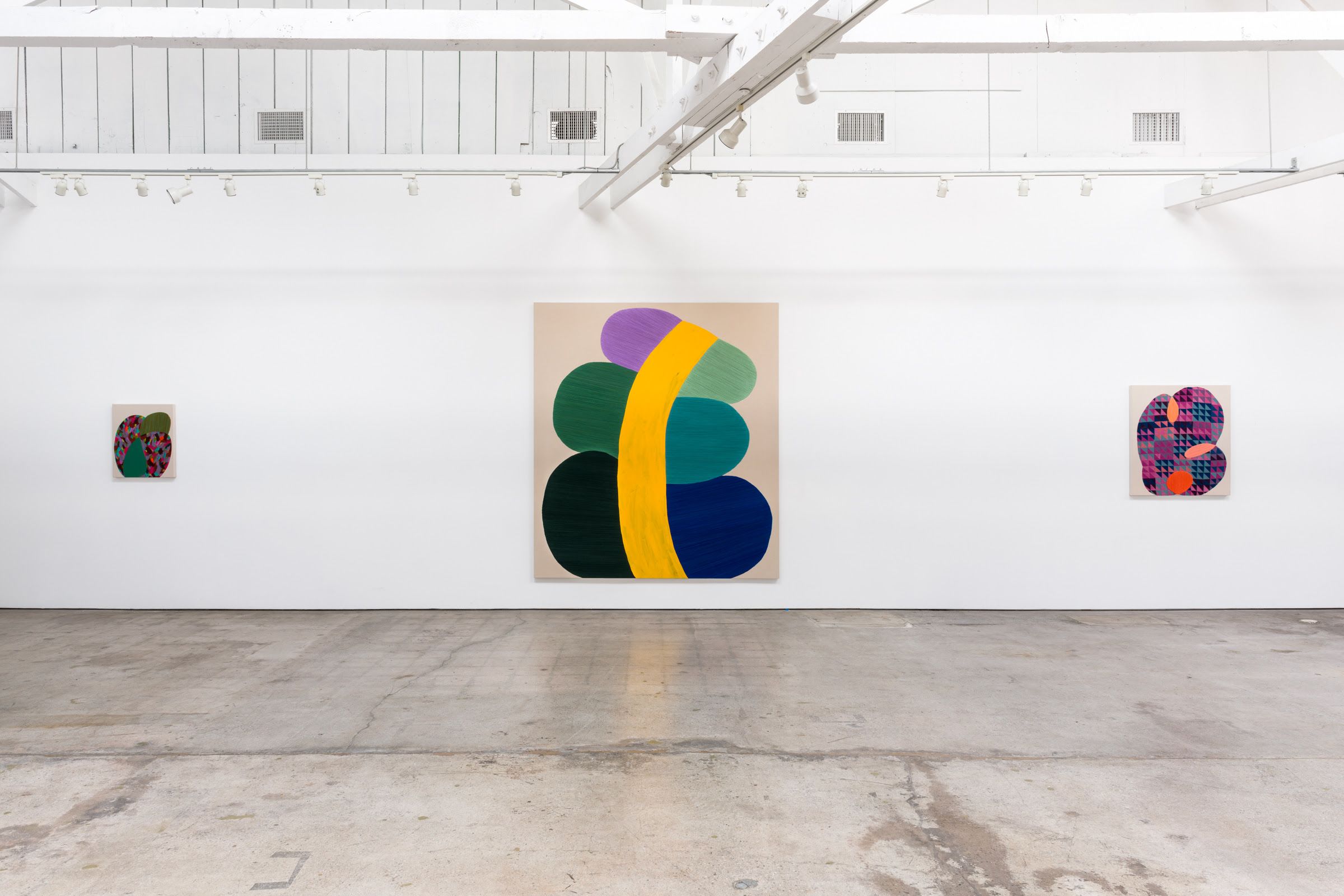 Abstract, colorful paintings hand in a white-walled gallery