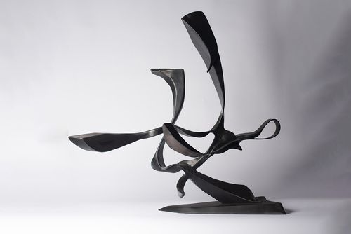 A black modern sculpture on a white surface