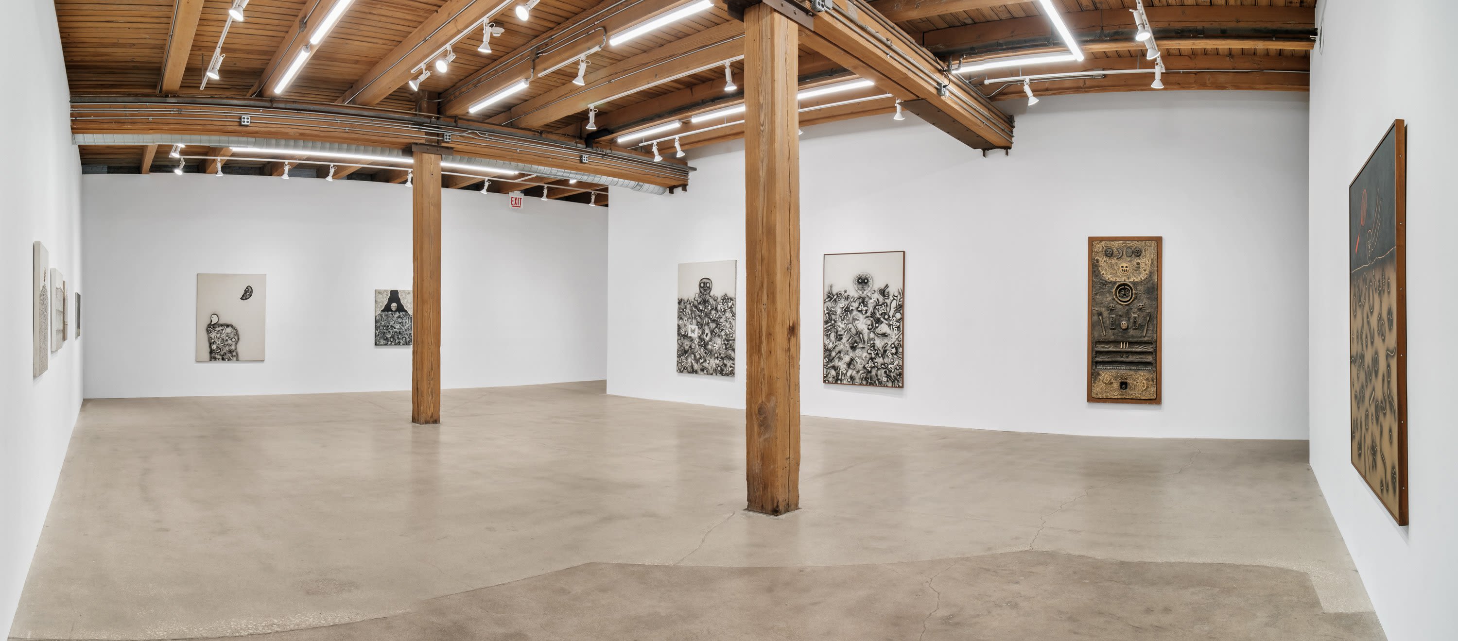 A white art gallery space with wooden pillars and a wooden ceiling
