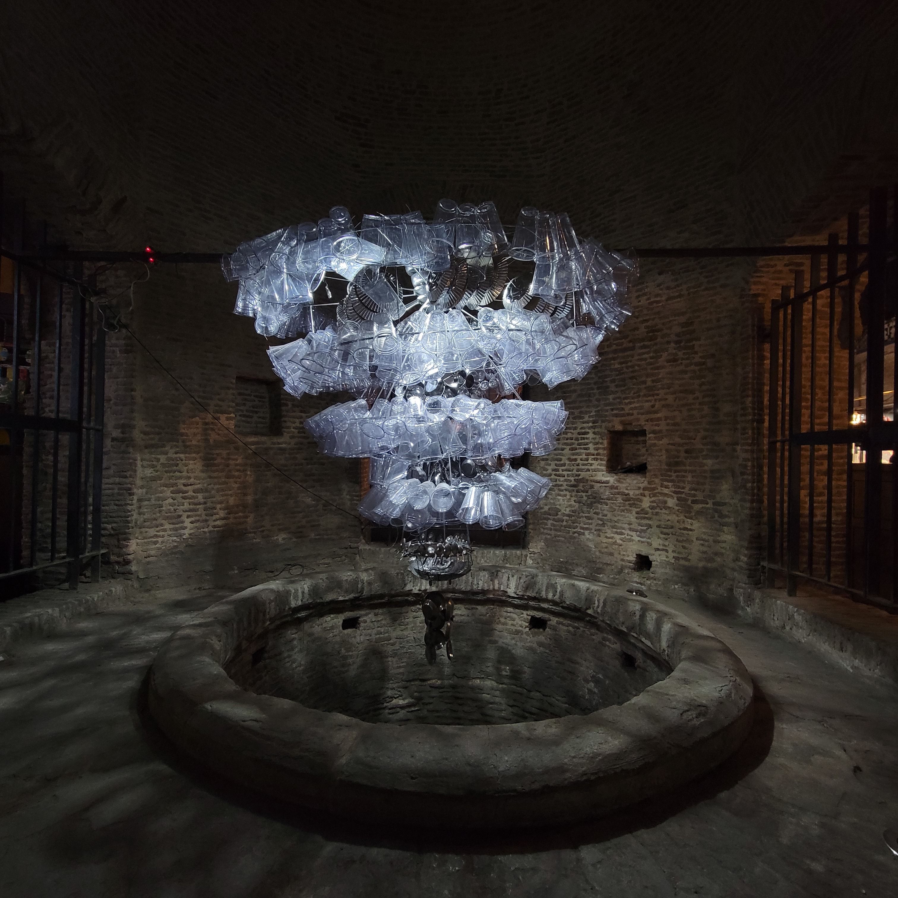 A chandeleir-like installation hands above a stone pit