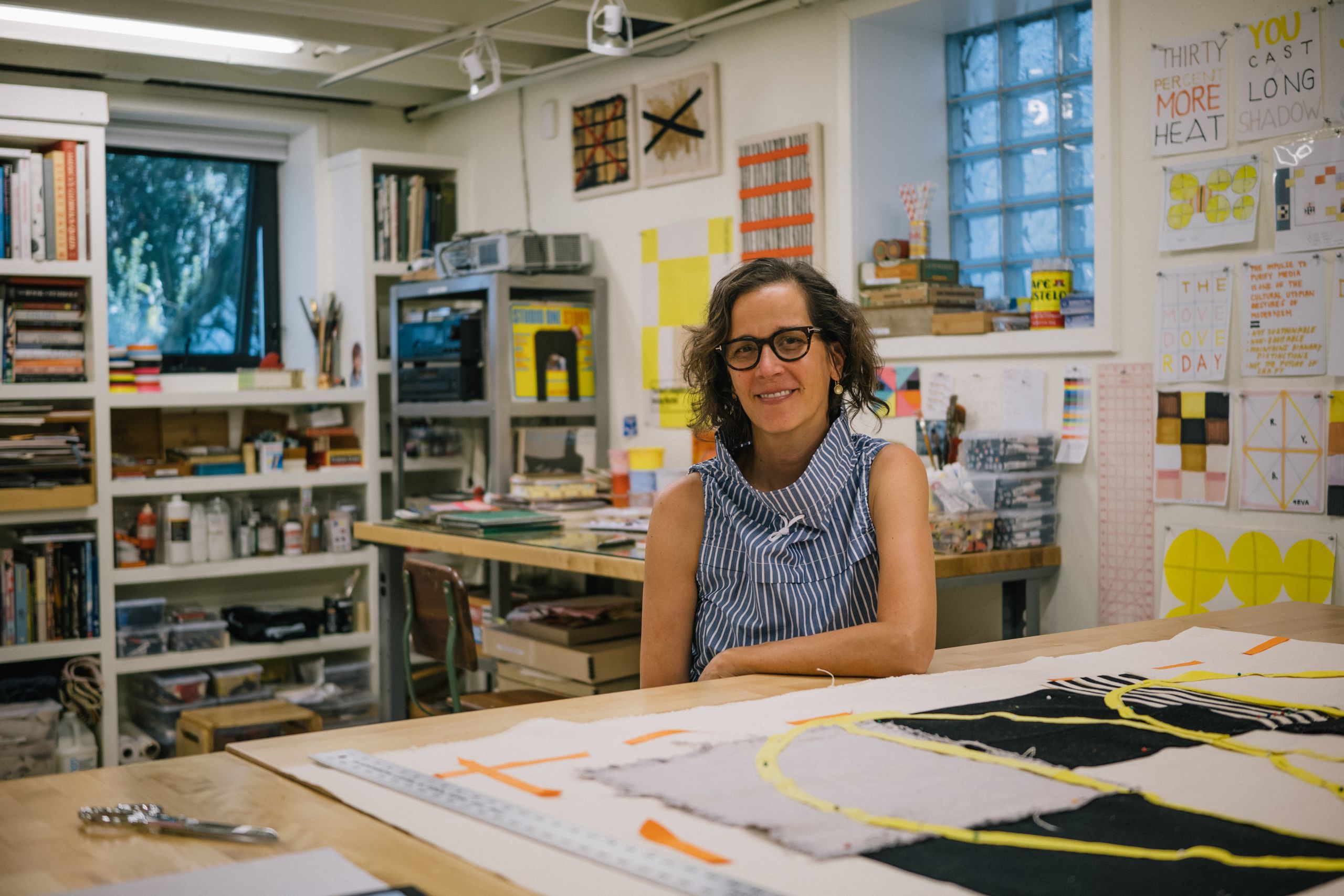 A female artist poses at a drafting table in her home studio