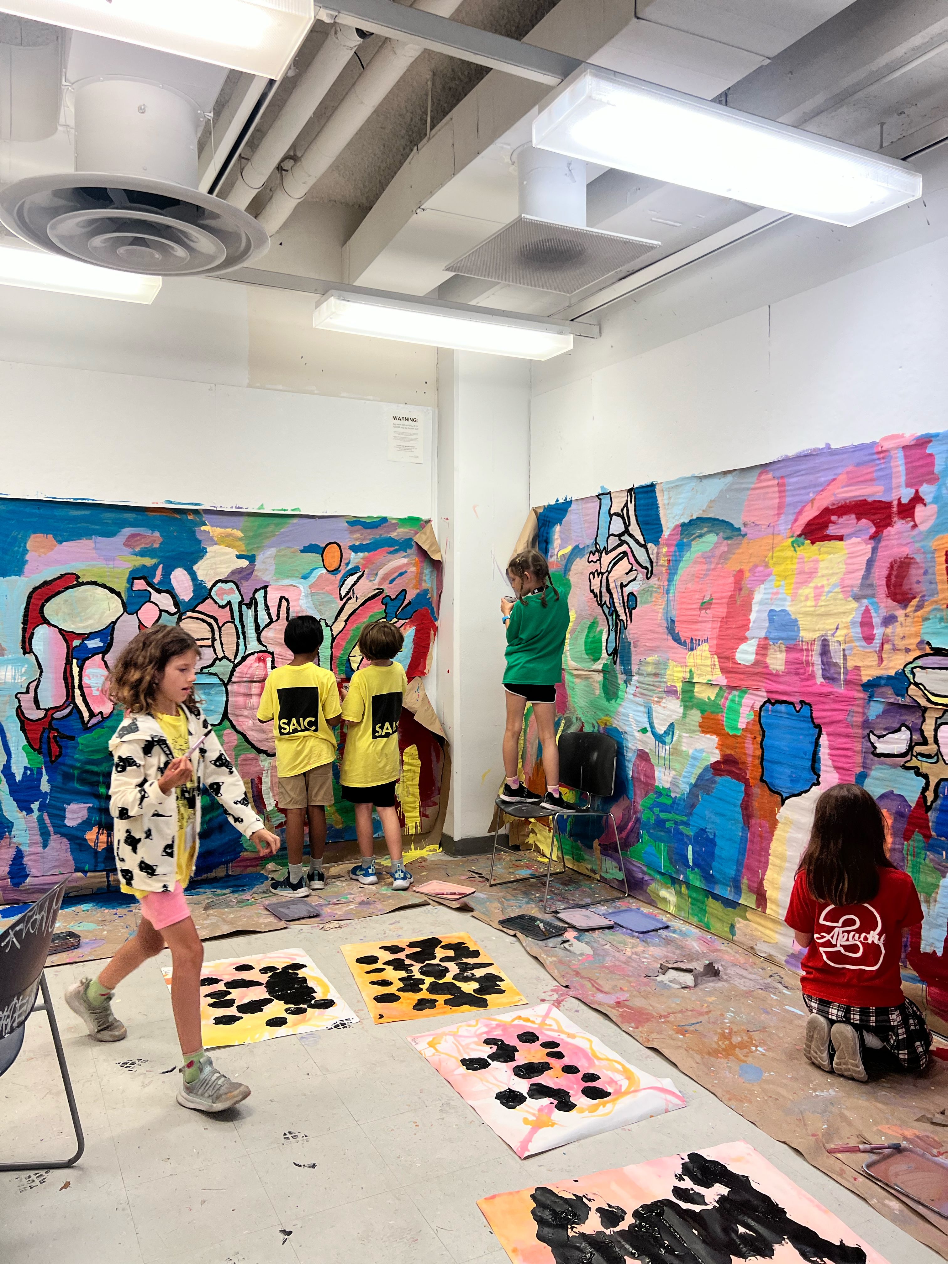 A colorful mural on the wall being completed by student artists