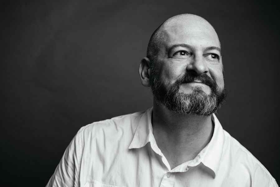 A black and white portrait of a male artist in a white shirt