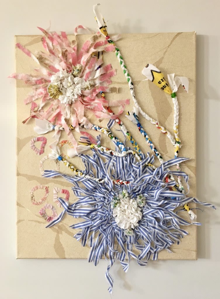 Pastel threads of blue and pink are woven into floral shapes on a brown backing