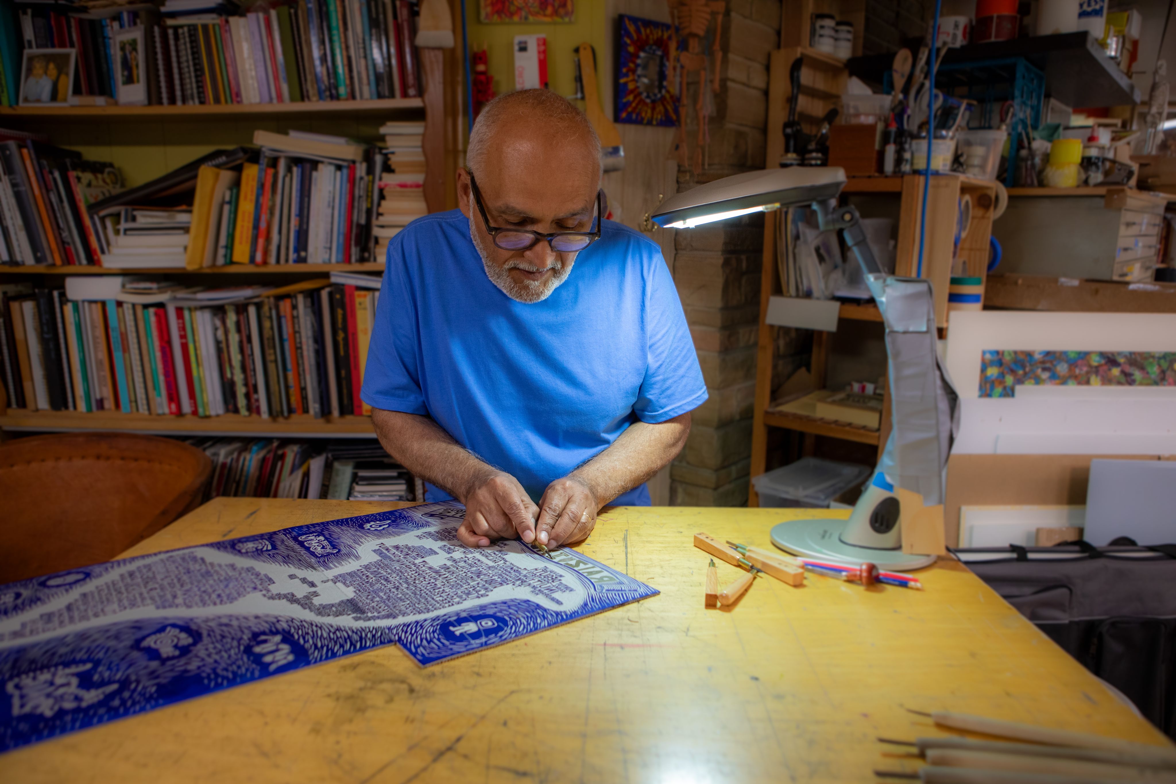 An artist does work on a blue and white print in his studio