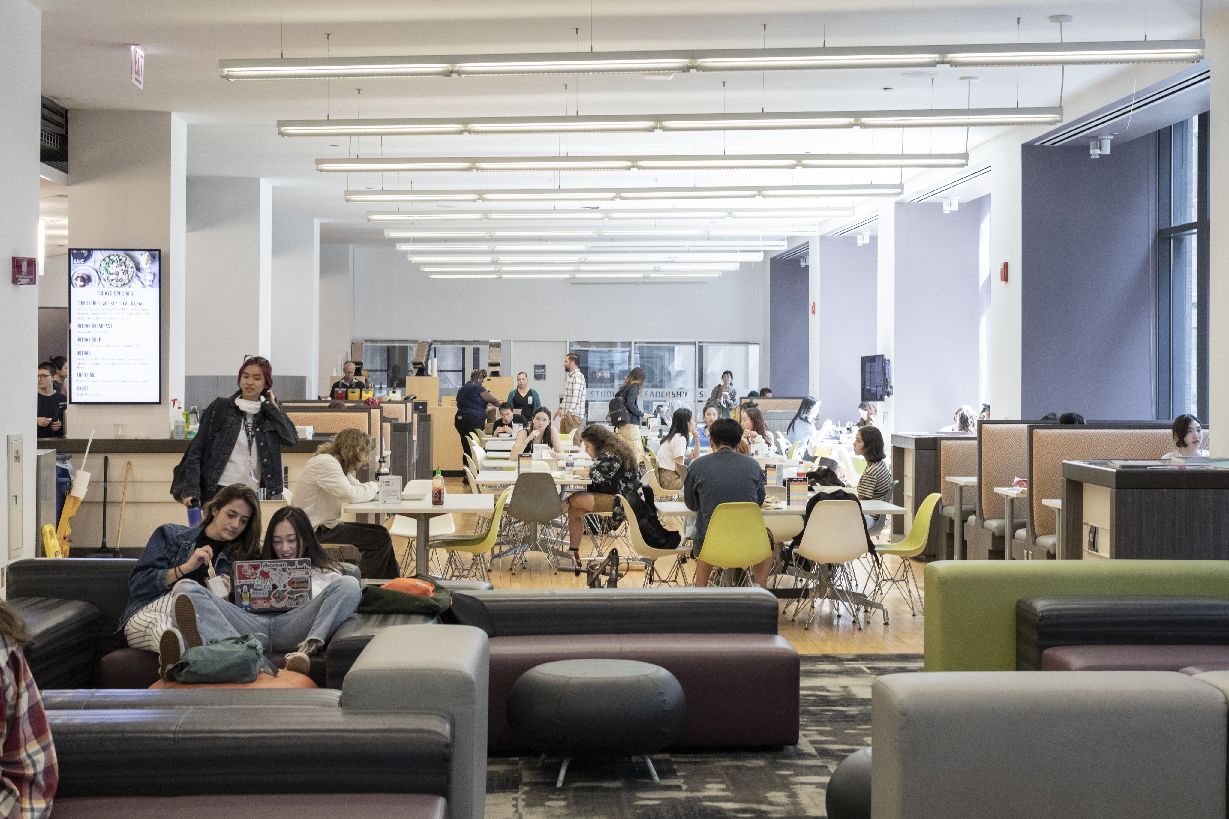A view of a modern student dining area, with students seated on couches and at tables
