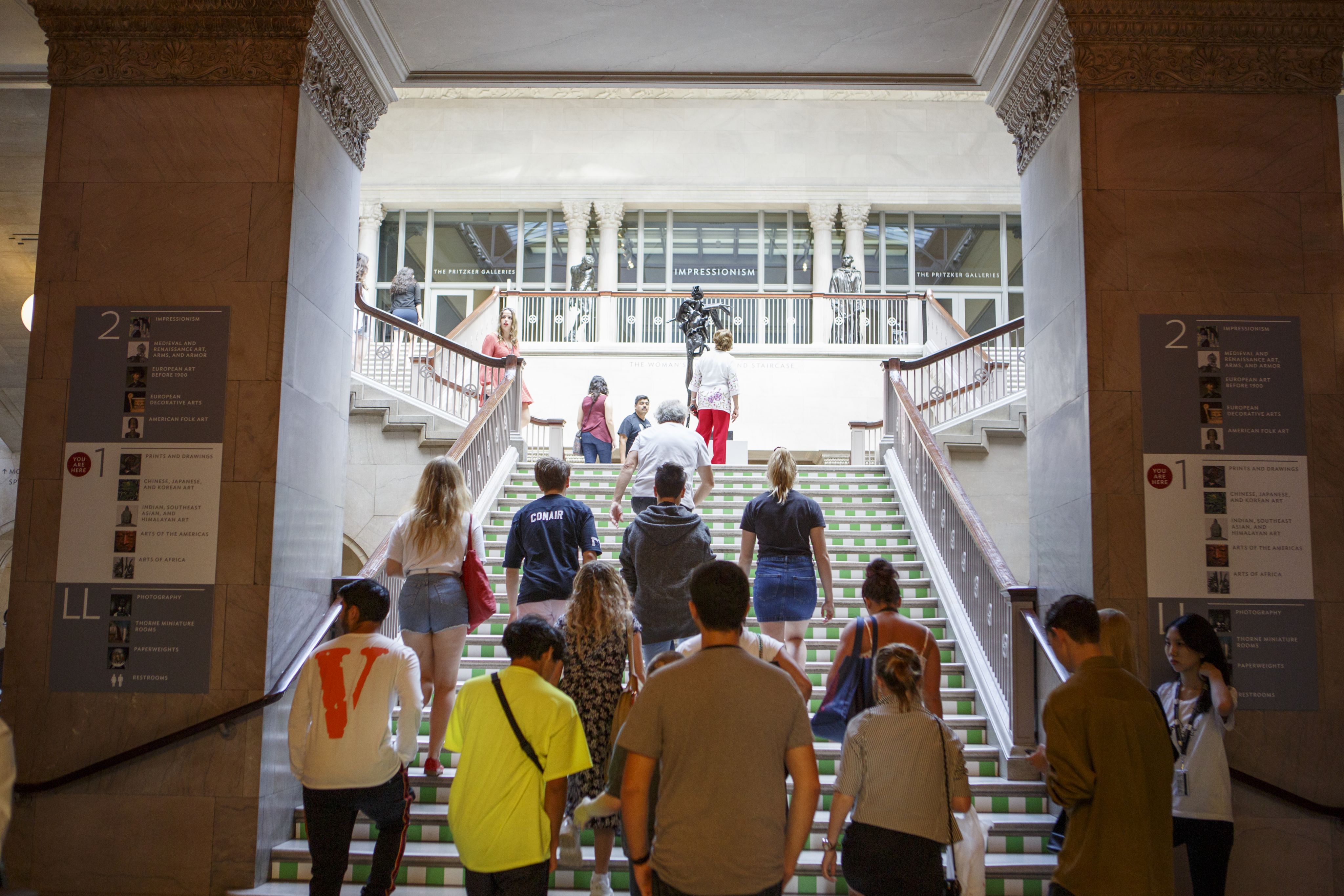 A group of students ascend the staircase of a museum