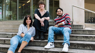 Three SAIC students smile as they sit on the steps of SAIC's campus.