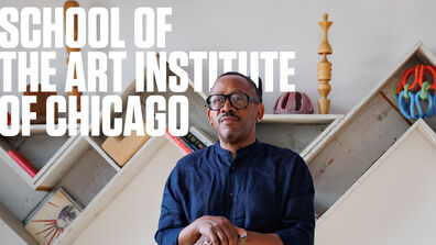 Portrait of Norman Teague, an adult Black person with a medium-dark skin tone, posing with a sculpture. "Fall 2025 School of the Art Institute of Chicago, a Biannual Magazine" is in bold text. 