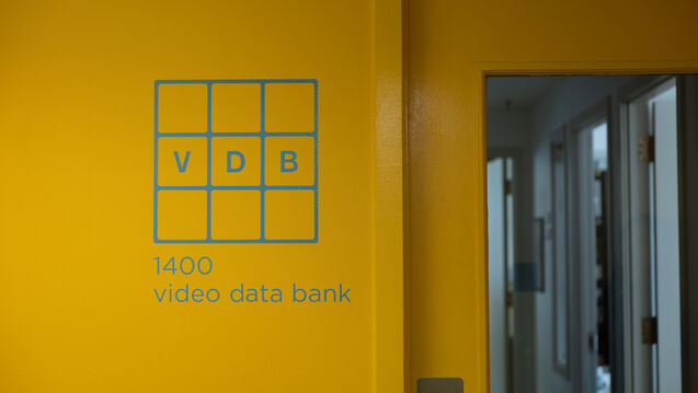 The blue Video Data Bank logo on a yellow wall. 