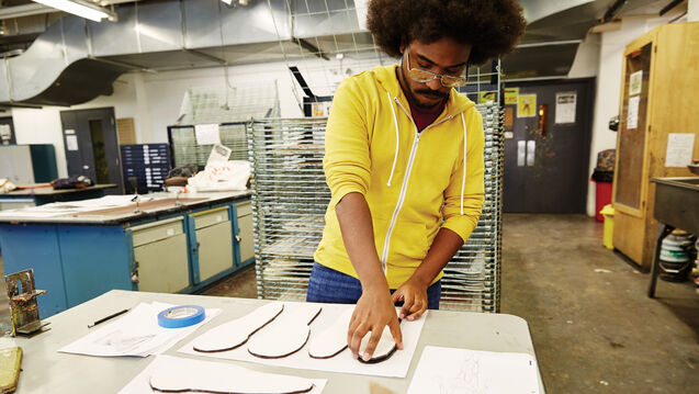 A student working in a studio with cardboard and paper. 