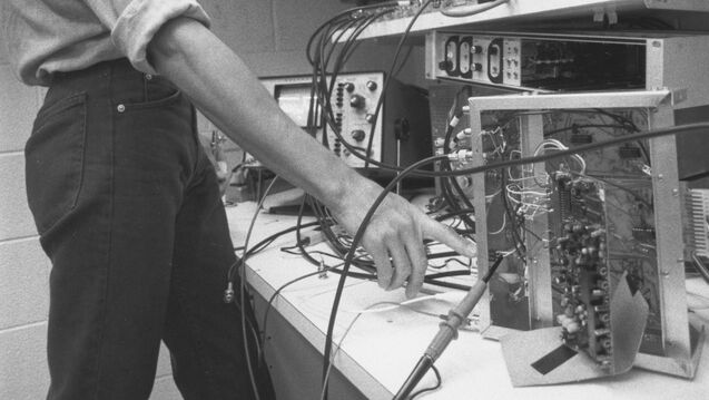 Black and white image of an art and tech student playing with CRT monitors and signals