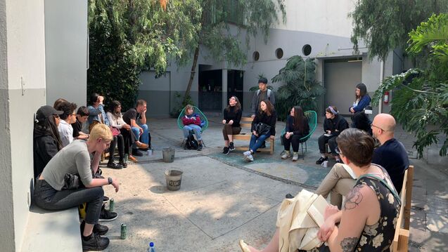 A group of students sitting and talking in an atrium.