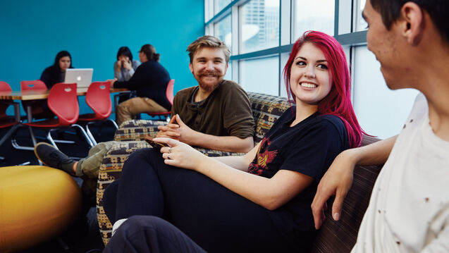 Students in a common area sitting on a couch and talking