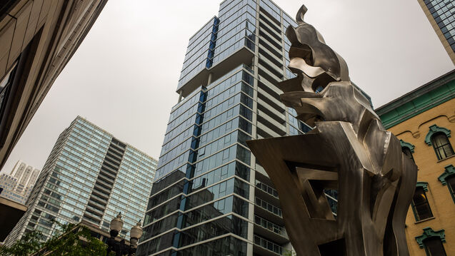 An abstract metal statue amongst skyscrapers