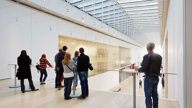 A group of people stand in a gallery hall.