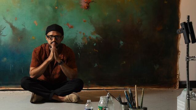 Artist  Bassim Al-Shaker sits in front of his artwork