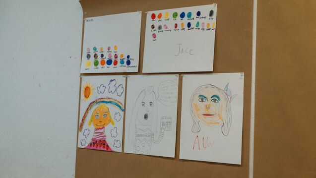 Children's drawings tacked to a wall