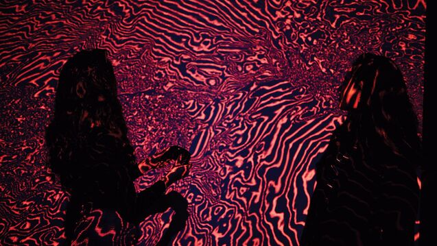 Two silhouettes of people viewing art piece
