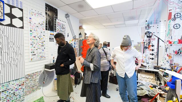 Three people standing indoors and viewing displayed art