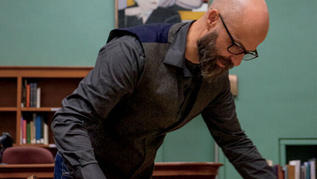 A professor leans over a table