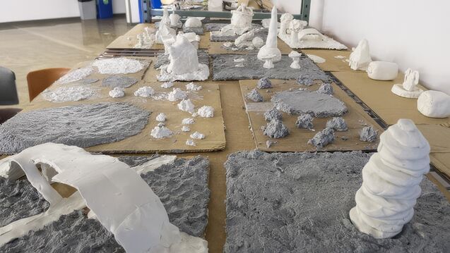 White and gray sculptures made of ceramic materials lined up on the floor.