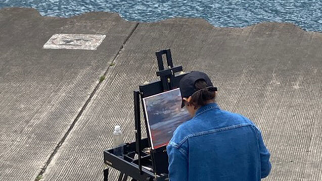 A student paints by the lakefront