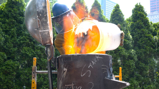 A person in protective gear pours molten metal.