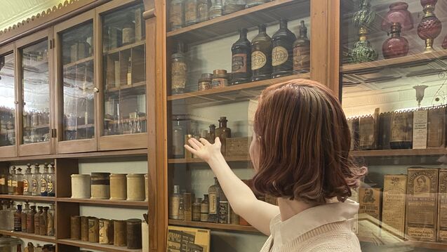 A person gestures toward a glass museum display. 