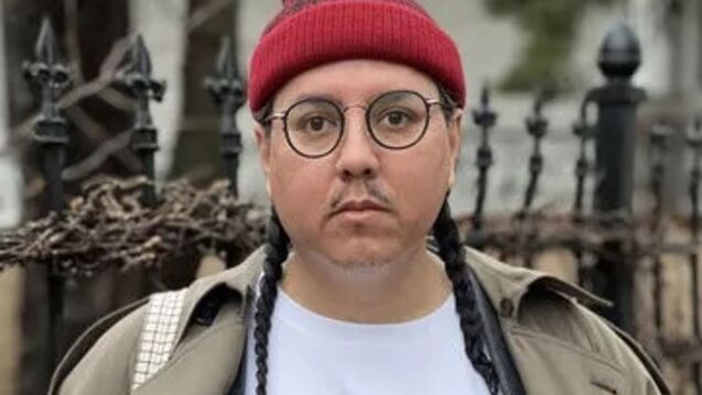 Portrait of Joshua Rios, an adult person with a medium skin tone, long hair in two braids, and glasses. 