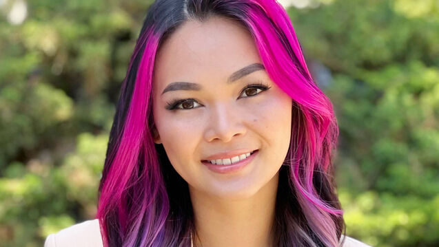 A profile photo of a young woman with pink hair