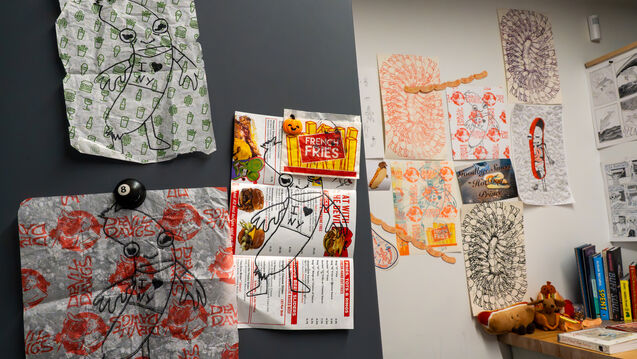 Multiple illustrated works hanging in a studio space. 