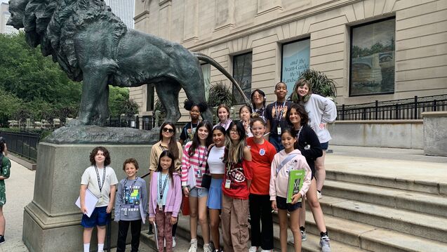 Middle school students of varying ethnicities, skintones, and genders, gathered on the steps of the Art Institute of Chicago. 